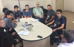 Jovens das equipes do Hackathon se reúnem com Prodabel e BHTrans. Dez pessoas estão sentadas ao redor de uma mesa. 