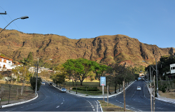 Avenida que leva ao parque dos mangabeiras com alguns carros na pista; Serra do Curral ao fundo, durante o dia. 