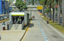 Estação Move Antônio Carlos, com pessoas entrendo e saindo; dois carros transitam na pista à direita. 