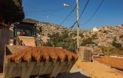 Trator carregando terra em Obra na Vila Fazendinha, ao fundo, comunidades do aglomerado da Serra.