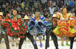 Três homens e três mulheres, dançando intercalados, realizam apresentação de quadrilha junina. 