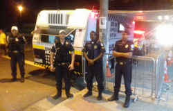 Quatro guardas municipais em frente a trailes da Guarda Municipal durante a noite. 