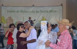Casais de idosos dançando forró, um deles caracterizado como "Noivos da roça".