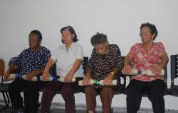 Quatro idosas segurando pesos durante atividade em grupo de prevenção de quedas.