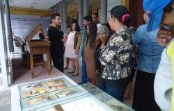 Cerca de quinze pessoas observando objetos em exposição no museu