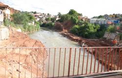 Foto feita de cima de uma ponte que passa sobre o Ribeirão do Onça. Nas margens do Ribeirão, há casas e áreas em obra.