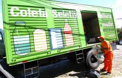 Funcionário da SLU coloca resíduos plásticos em caminhão de coleta seletiva, durante o dia. 