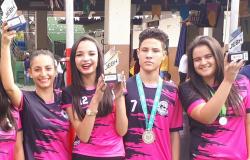 Quatro participantes dos Jogos Escolares de Belo Horizonte, três garotas e um garoto, exibem suas medalhas em sorriem. 