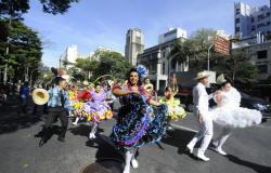A foto mostra um grupo de dançarinos de quadrilha desfilando na avenida Afonso Pena em um dia de céu claro, sem nuvens.
