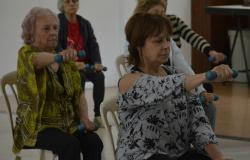 cinco idosas praticando exercícios físicos erguendo pesos