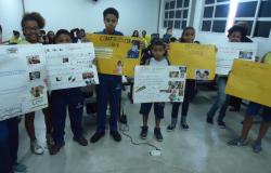 Oito crianças em sala cheia segurando cartazes sobre a conferência livre