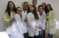 8 jovens alunos da Rede Municipal vestindo jaleco com logo do projeto de iniciação científica