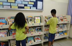 Duas crianças na biblioteca escolar escolhendo livros na prateleira