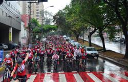 Cerca de 400 ciclistas pedalam vestindo camisas vermelhas em dia chuvoso por uma rua de Belo Horizonte